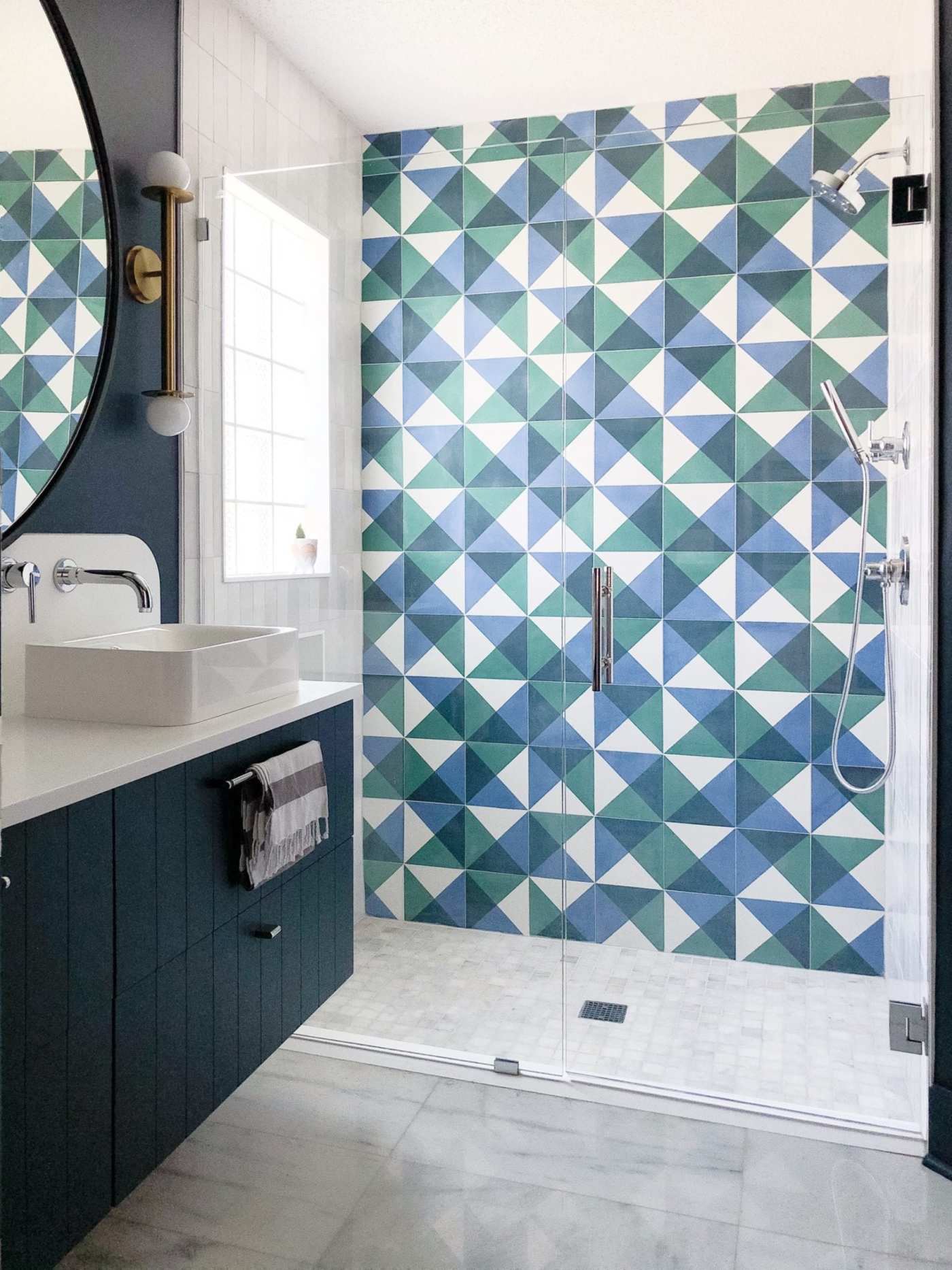 a bathroom with a blue and green tiled shower.