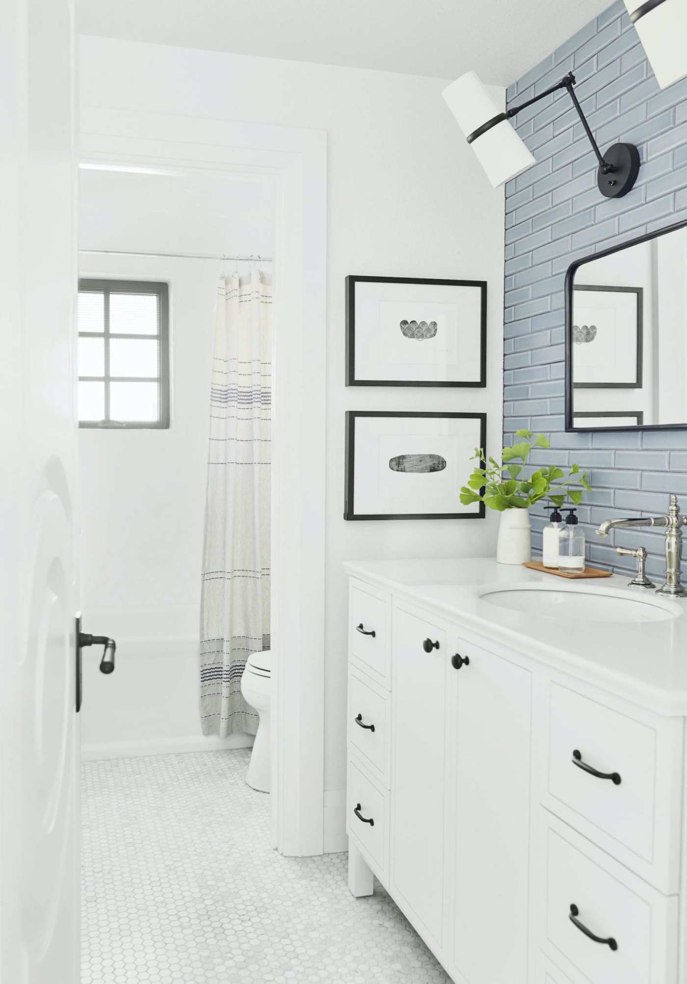 a white bathroom with blue tiled sink backsplash and a mirror.