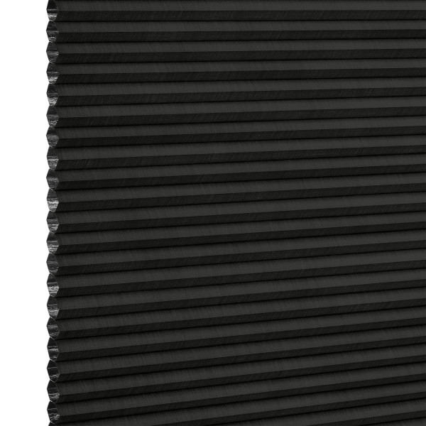 Black cellular (honeycomb) pleated blind, lowered and closed with left-edge cells exposed, blocking light; close-up studio product shot on neutral white background with even lighting.