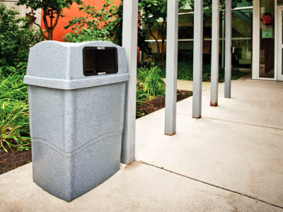 outdoor waste container with hinged lid made from durable LDPE plastic sitting outside at a city library entrance