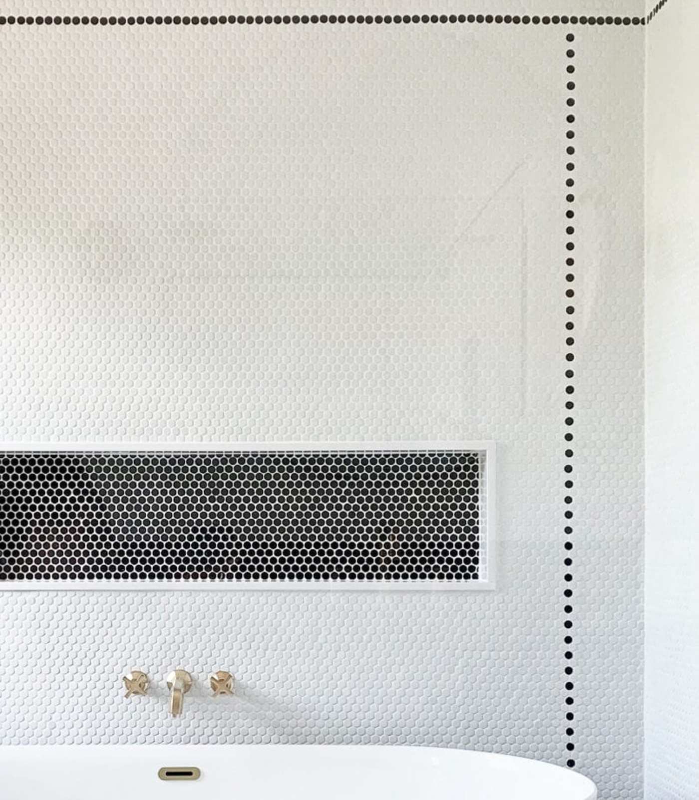 a bathroom with black and white tile and a tub.