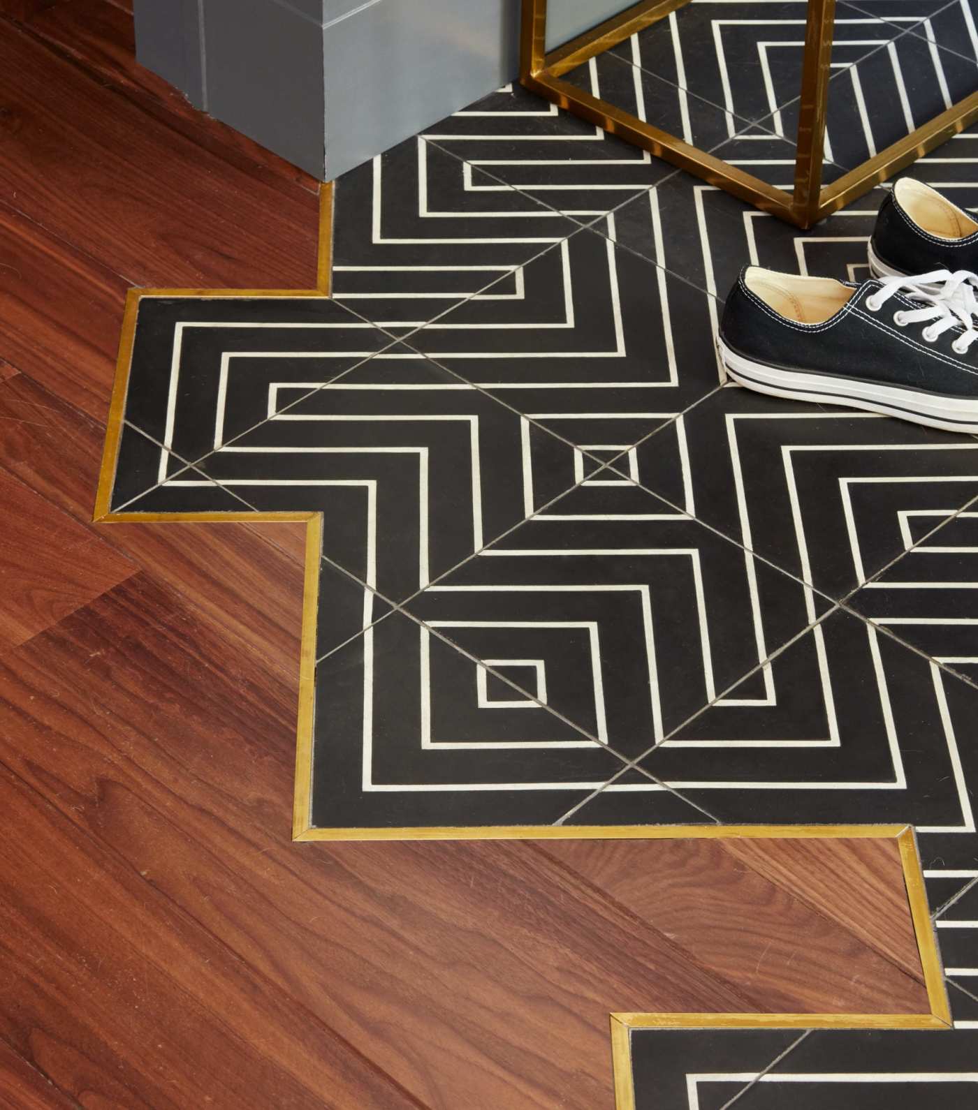 a floor with wooden planks and black, white, and gold tiles.