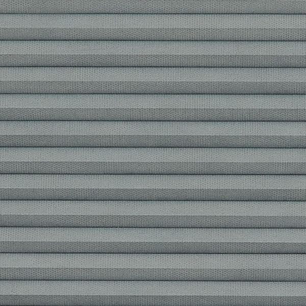 Gray pleated cellular window shade with horizontal accordion folds, fully lowered and closed, textured fabric and uniform spacing; close-up view filling frame under soft, diffuse lighting.