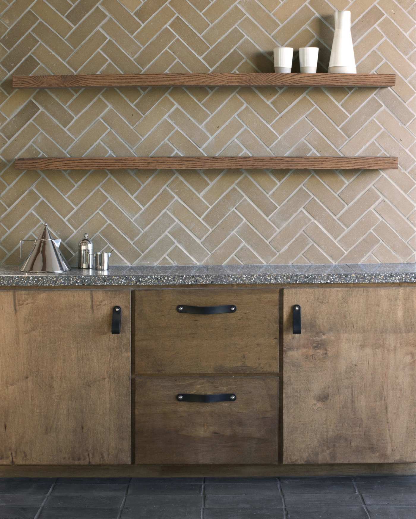 a kitchen with wooden cabinets and a herringbone tile backsplash.