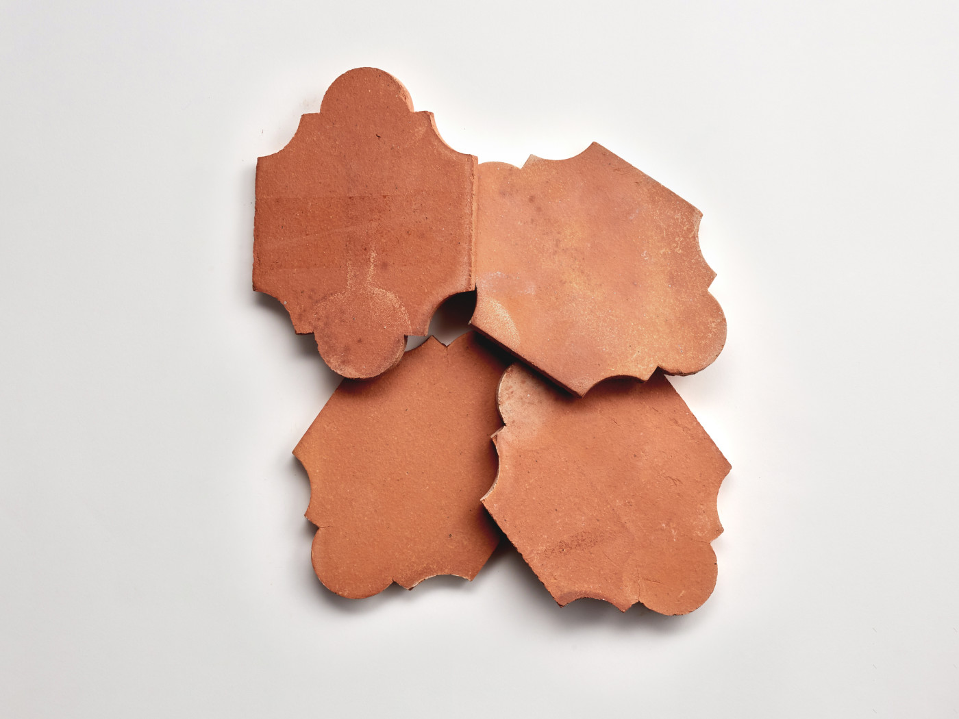 four pieces of red clay tile on a white surface.