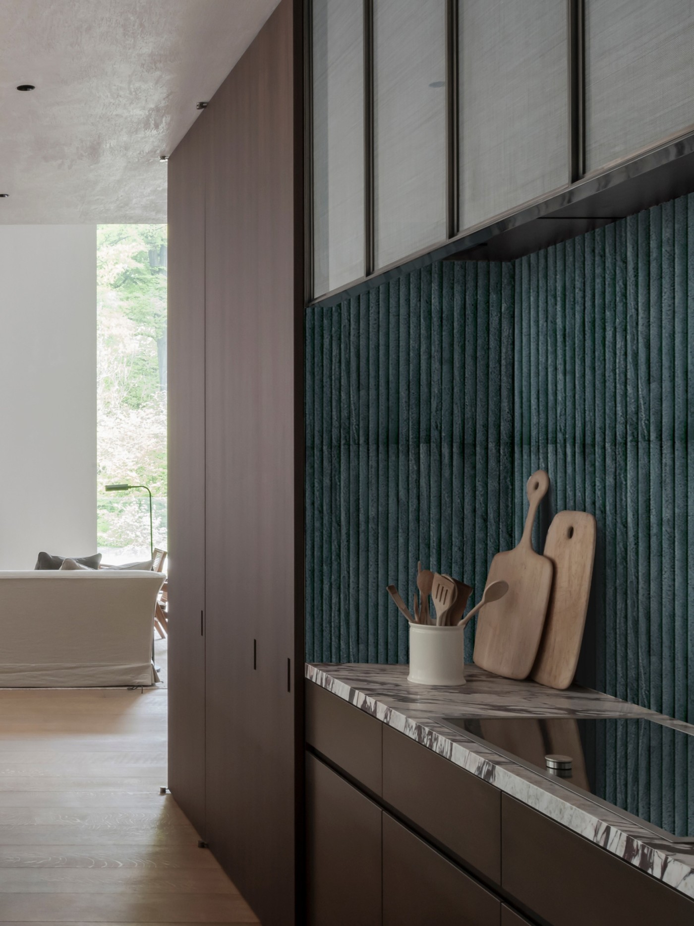 a kitchen with a marble counter top, vertical tile backsplash, and wooden cabinets.