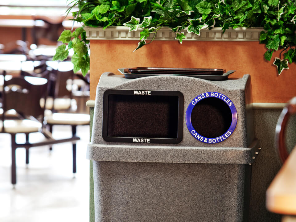 indoor double opening waste and recycling bin with a built-in food tray shelf on the lid placed in a college campus cafeteria