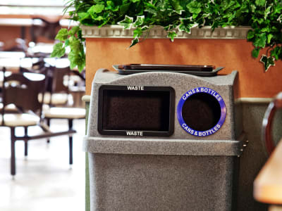 indoor double opening waste and recycling bin with a built-in food tray shelf on the lid placed in a college campus cafeteria