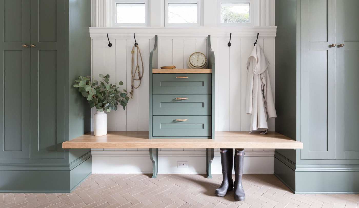 a mudroom with green cabinets and a wooden bench.