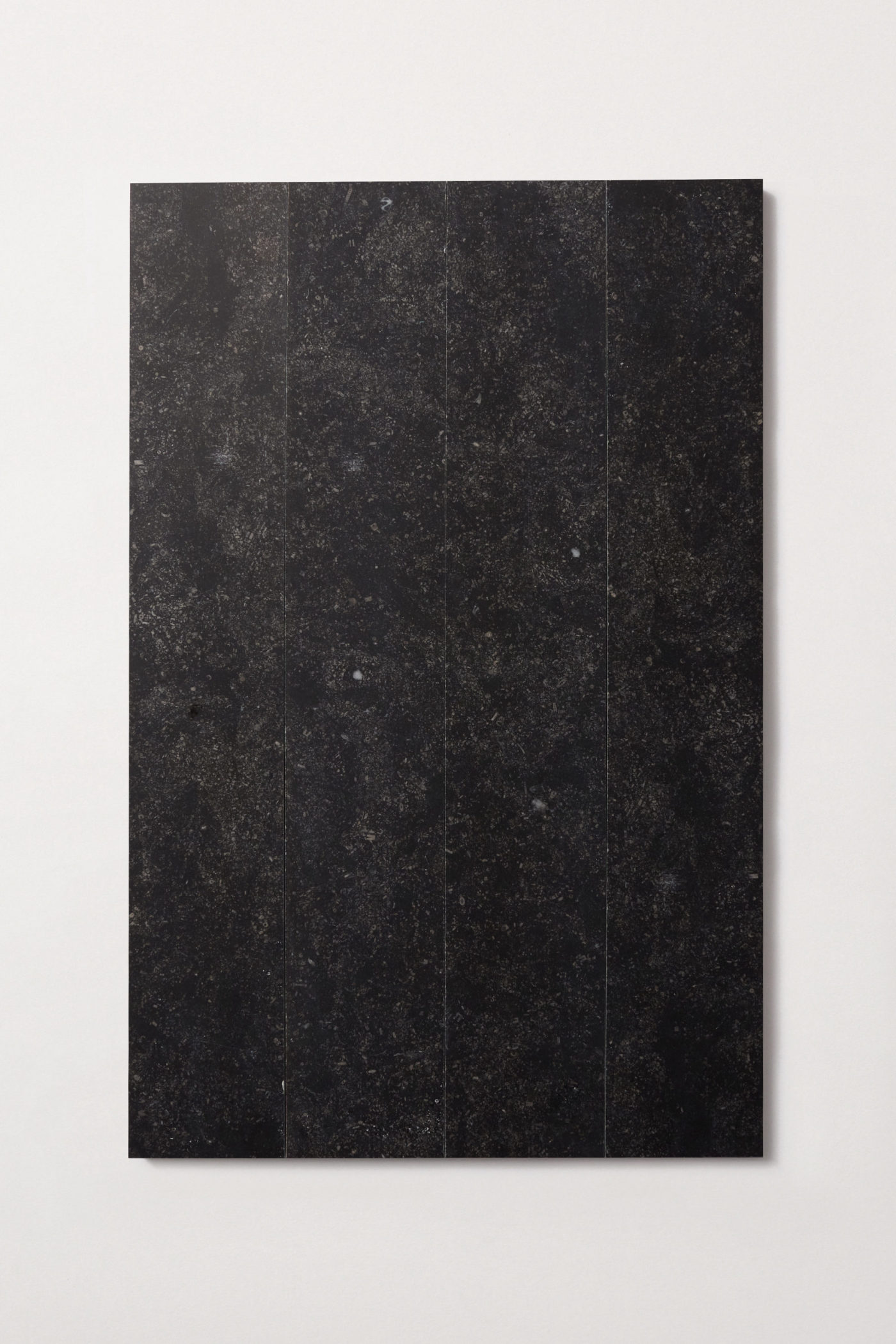 four black rectangle limestone tiles on a white surface.