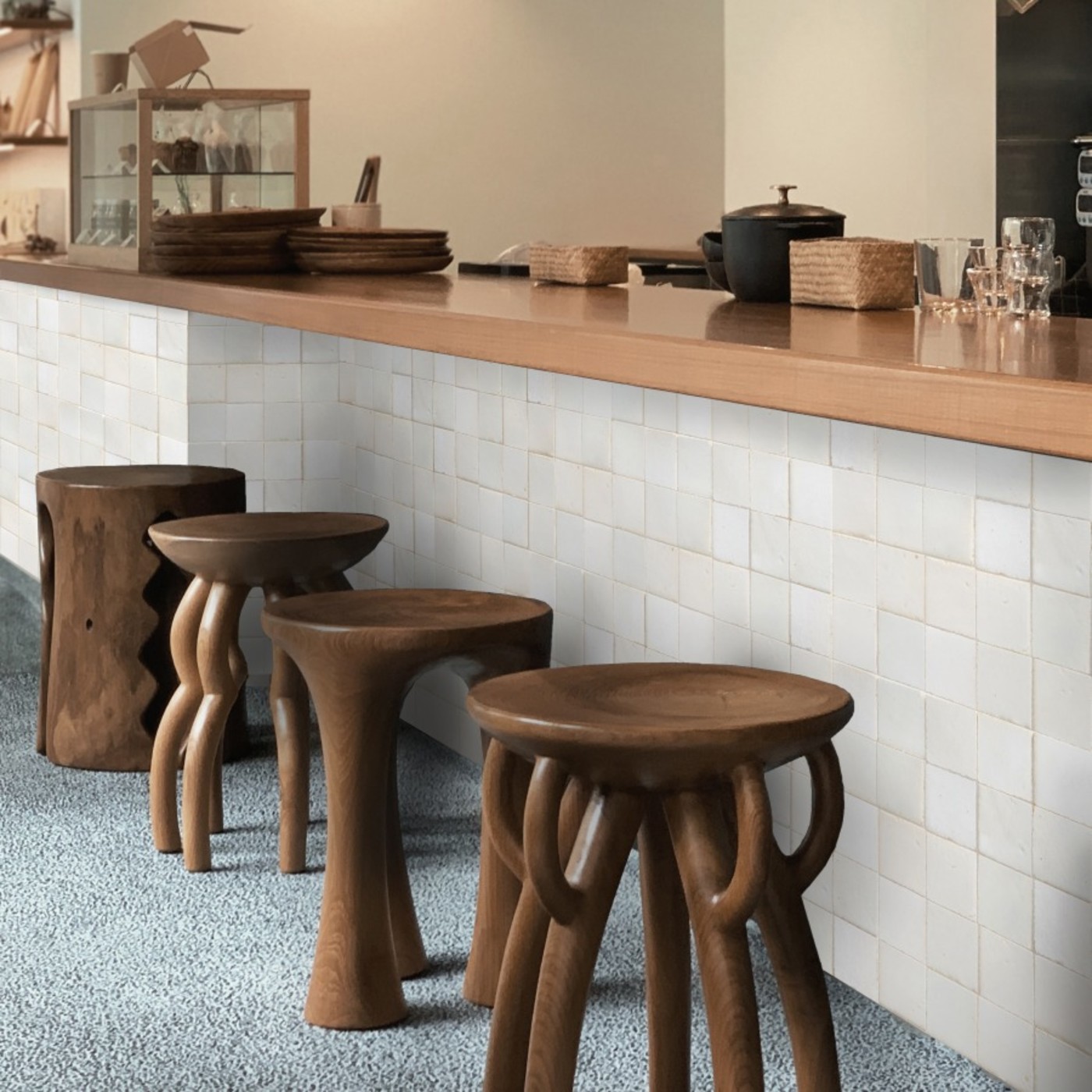 a bar with wooden stools and a white tiled counter wall.