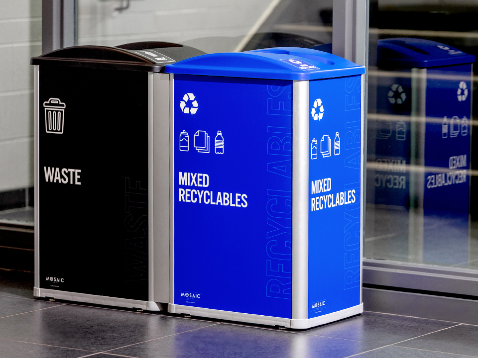 waste and recycling container station in a fitness center with bold colored signs and labels