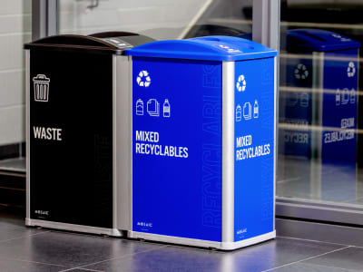 waste and recycling container station in a fitness center with bold colored signs and labels