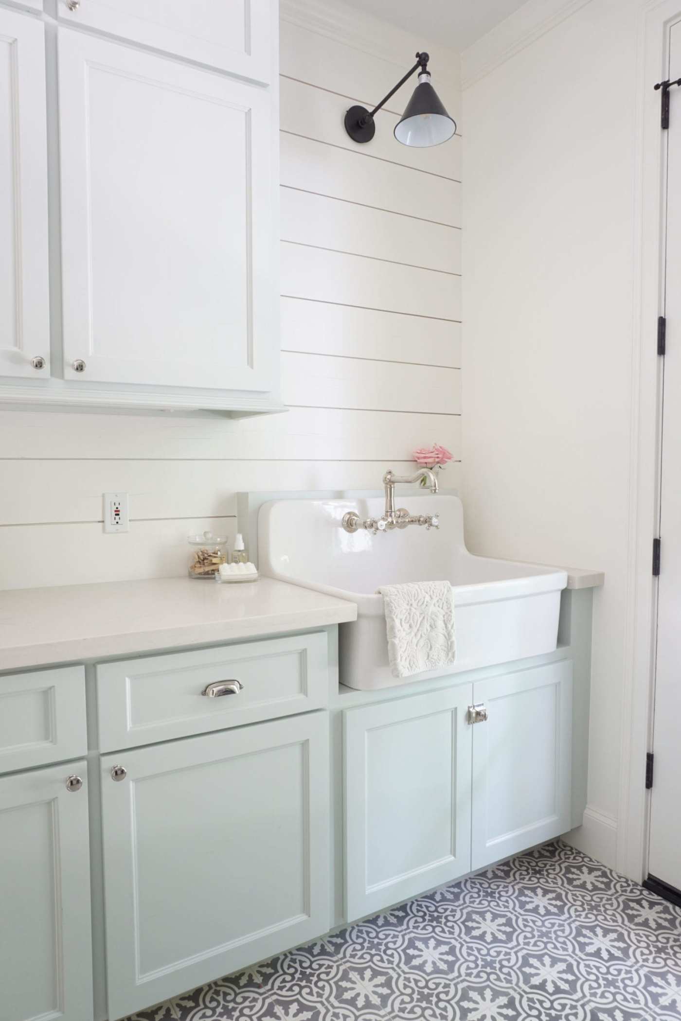 a laundry room with light blue cabinets and a tile floor.