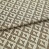 Woven upholstery fabric with repeating cream and brown triangular geometric pattern; folded across the middle, lying flat; close-up studio lighting emphasizes texture and tight weave.