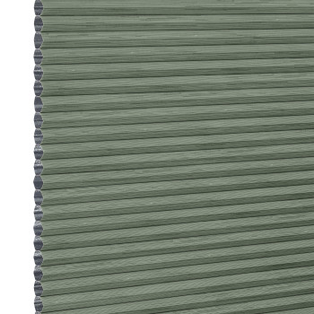 Cellular honeycomb blind — sage-green pleated fabric fully lowered with exposed hexagonal cells along the left edge; blocking and softly filtering light in a neutral interior.