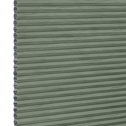 Cellular honeycomb blind â€” sage-green pleated fabric fully lowered with exposed hexagonal cells along the left edge; blocking and softly filtering light in a neutral interior.