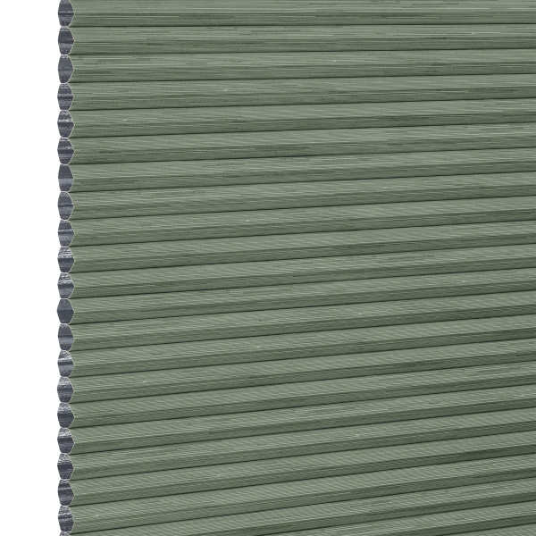 Cellular honeycomb blind — sage-green pleated fabric fully lowered with exposed hexagonal cells along the left edge; blocking and softly filtering light in a neutral interior.