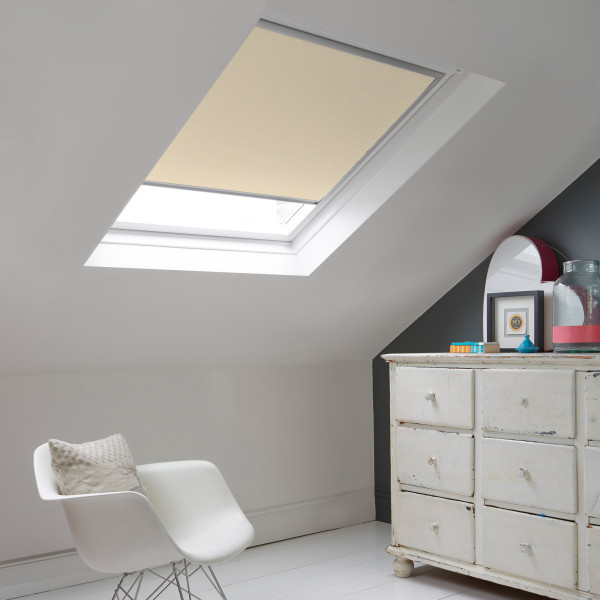 Room with white eaves wall, dark blue-grey wall to right with a shabby chic white drawer unit, a contemporary white chair, white painted floorboards and a skylight blind in pale cappucino.