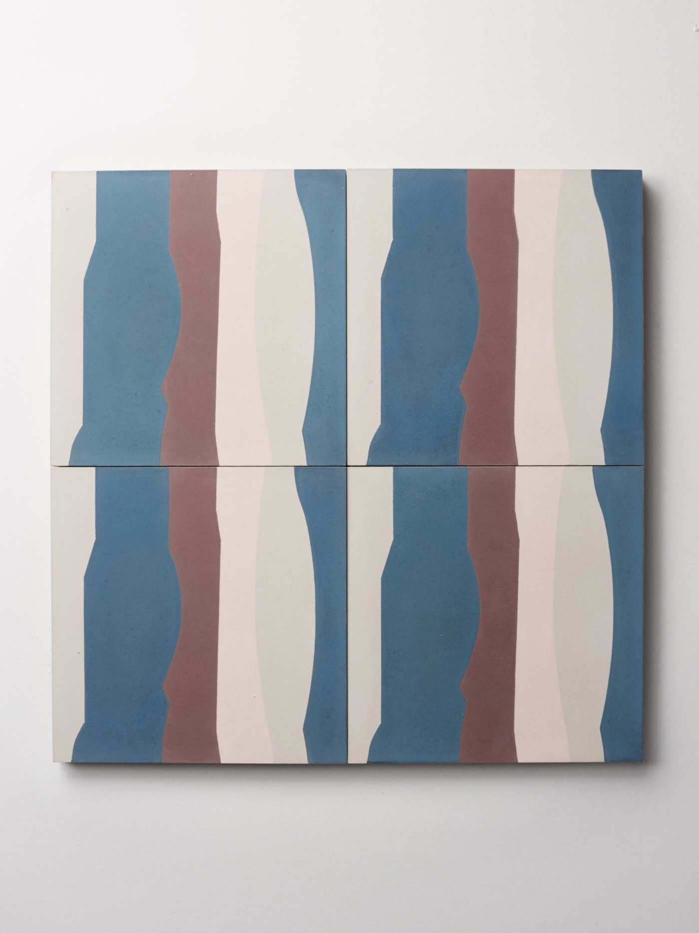 four tiles with beige, blue, brown and white strips on a white surface.