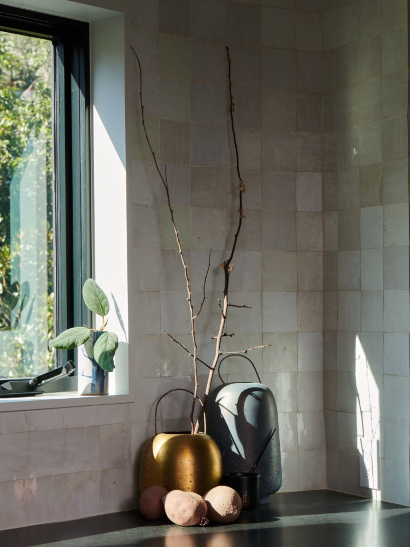 a kitchen window with a plant on the counter and white tiled backsplash walls.