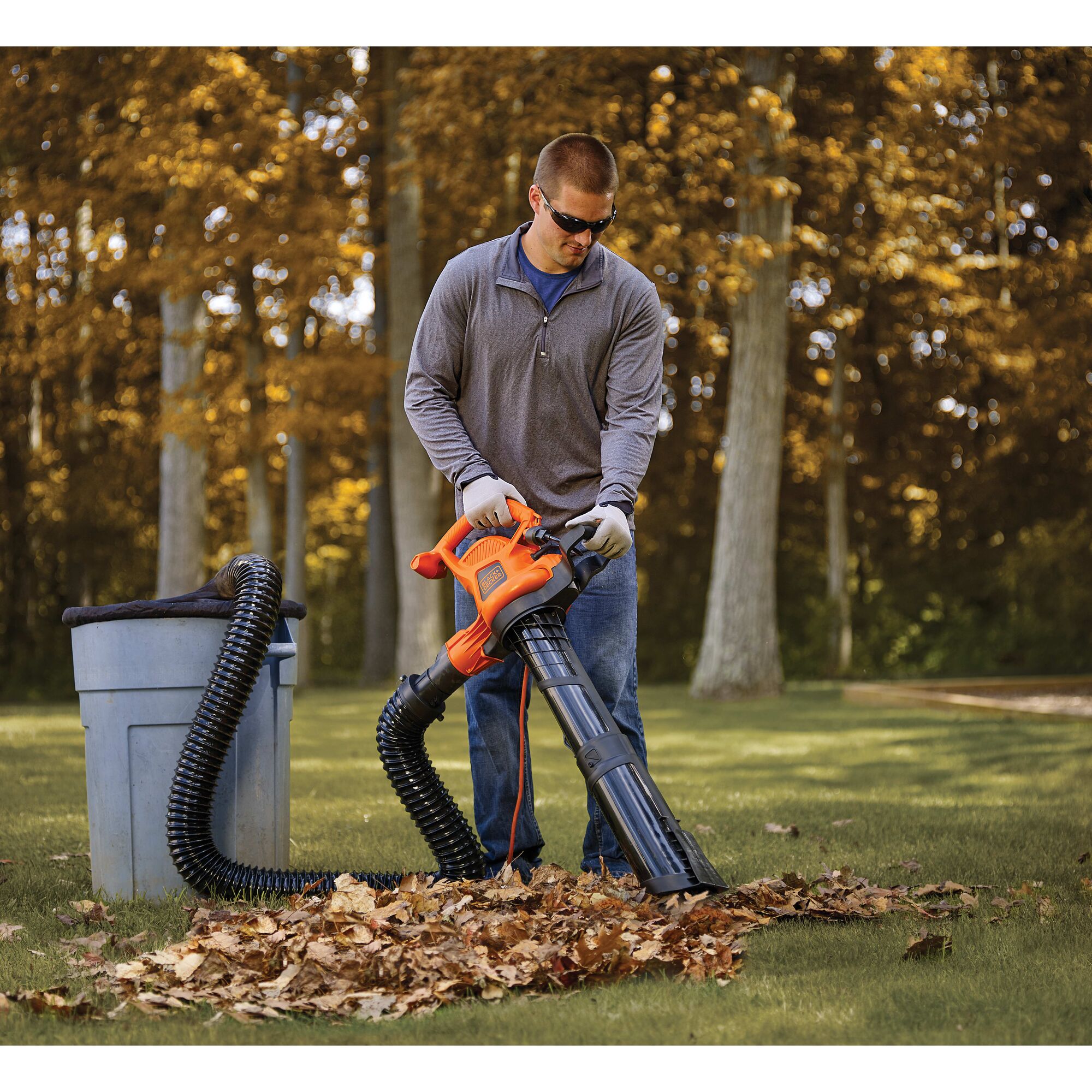 Man using BLACK+DECKER leaf collection system in front yard of home