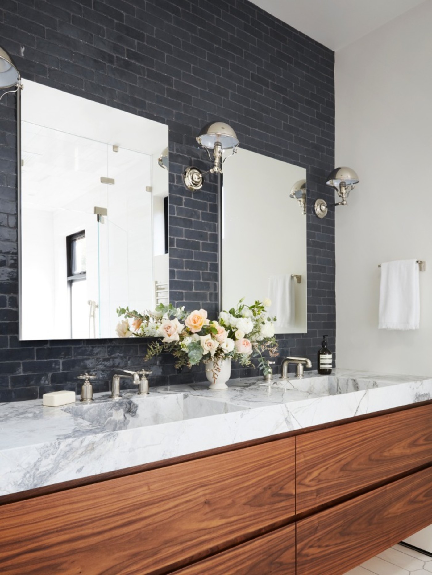 a bathroom with black tile backsplash and marble counter tops.