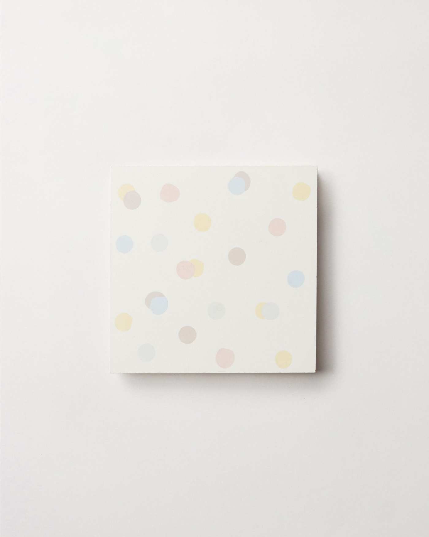 a white tile with multicolored polka dots on a white surface.