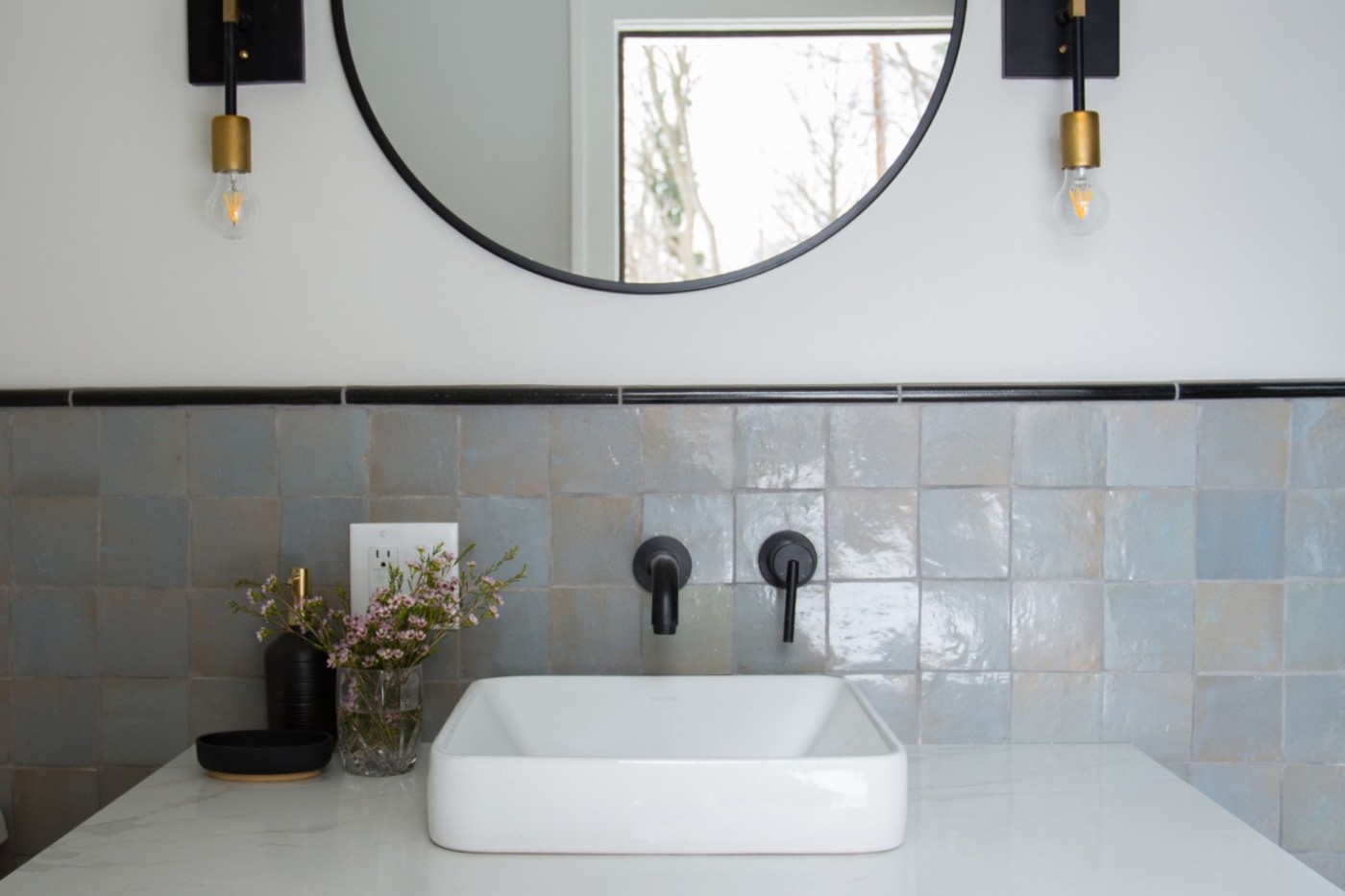 a bathroom sink with grey tile backsplash.