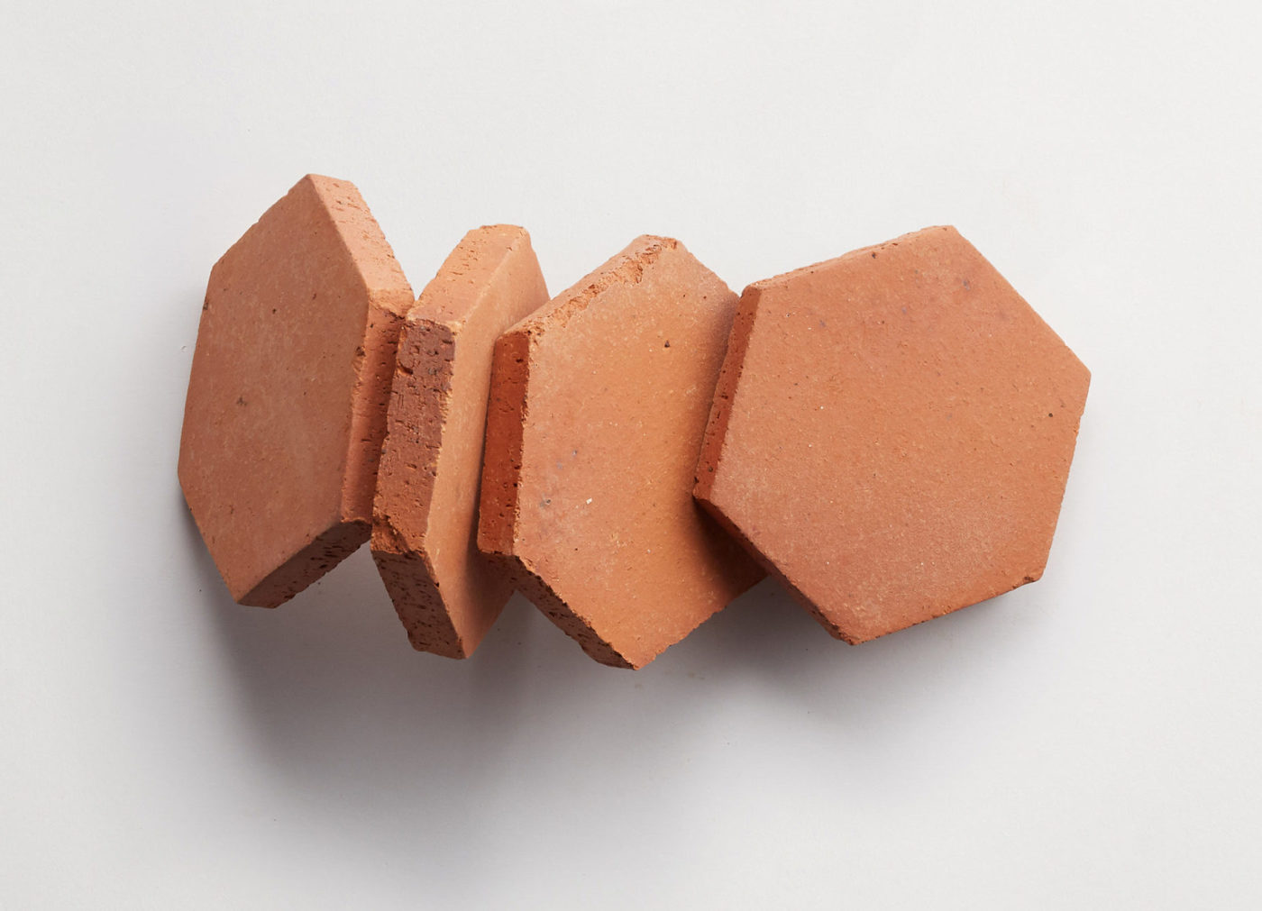 4 red, hexagonal terracotta tiles on a white background.