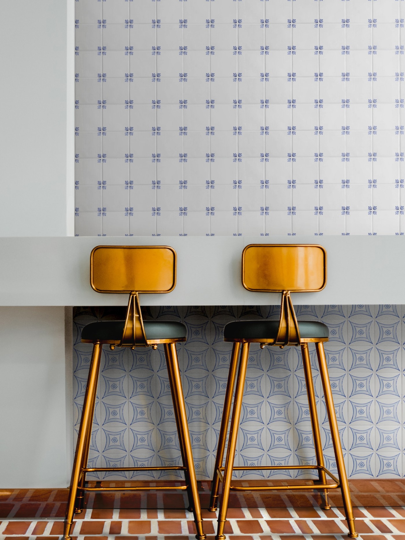 a table with two stools in front of a blue and white tiled wall.