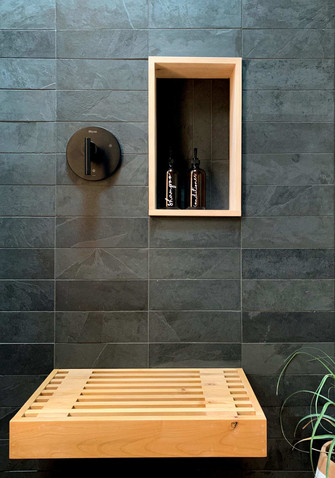 a wooden bench in a slate tiled shower.