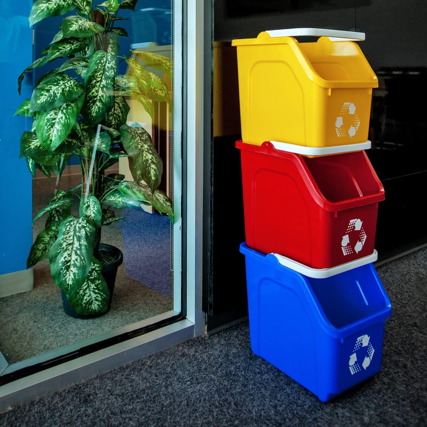 three brightly colored recycling bins stacked on top of each other in a college office area