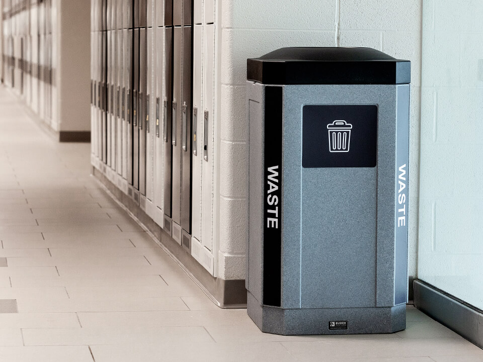 single indoor waste bin with color coded lid and body labels shown in the hallway of a high school