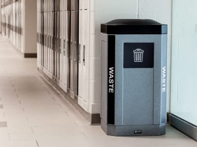 single indoor waste bin with color coded lid and body labels shown in the hallway of a high school