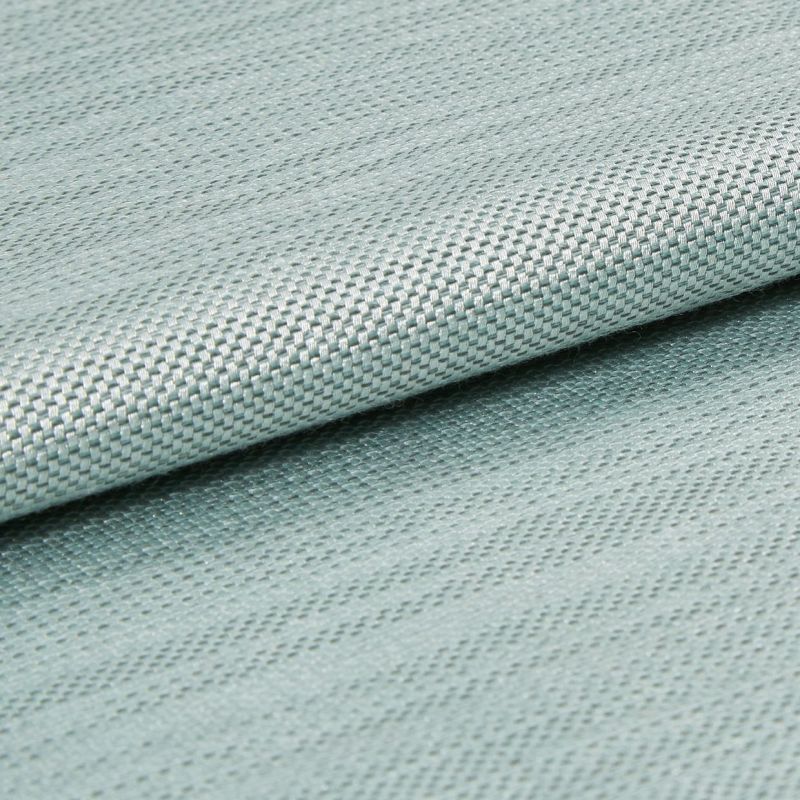 Light blue woven fabric with tight basketweave texture, folded across the frame creating an overlapping edge; close-up studio shot with soft, even lighting and shallow depth of field.