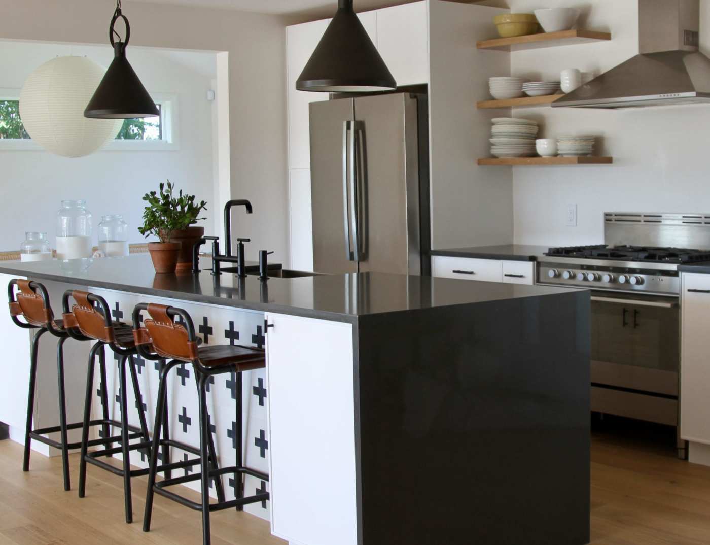 a white kitchen with black counter tops and stools.