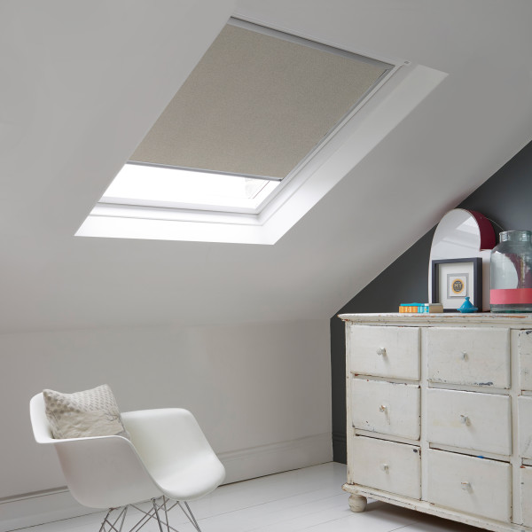 Room with white eaves wall, dark blue-grey wall to right with a shabby chic white drawer unit, a contemporary white chair, white painted floorboards and a skylight blind in pale grey with a subtle glitter effect.