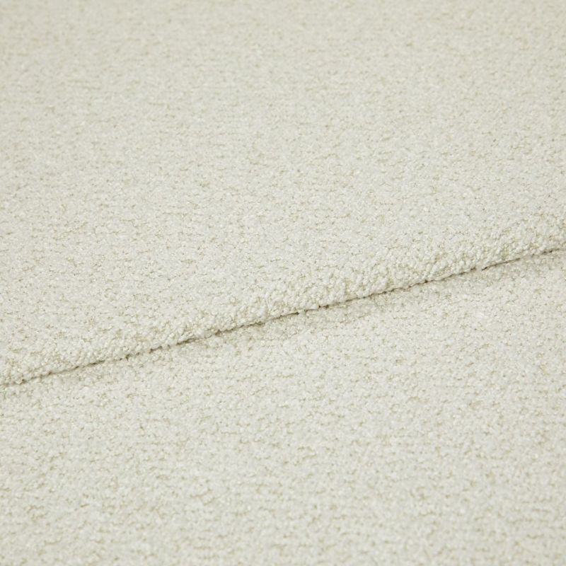 Cream bouclÃ© fabric folded into overlapping layers, showing a horizontal seam; close-up view with soft, even lighting emphasizing the looped texture in a neutral studio setting.