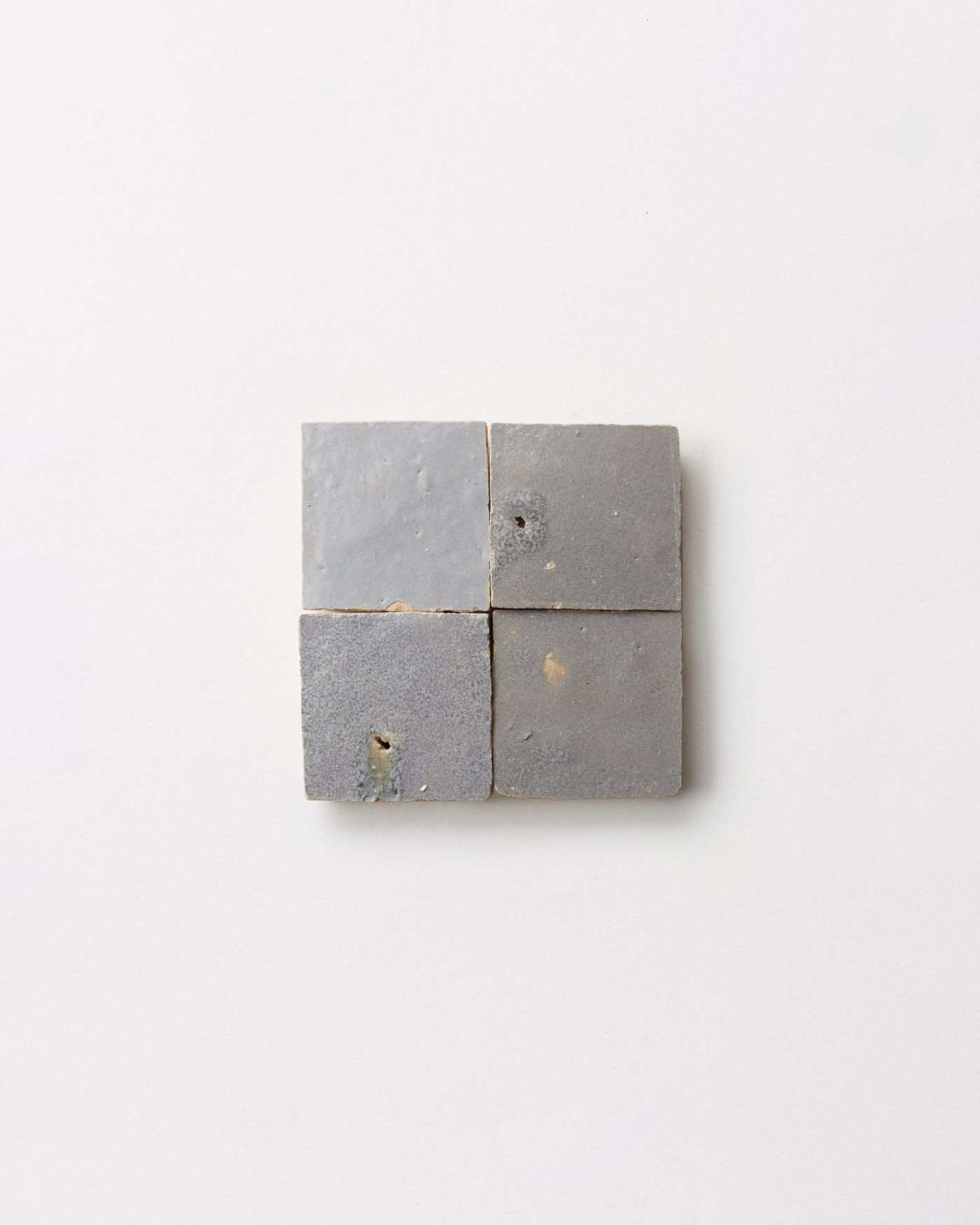 4 square pieces of gray tile on a white surface.