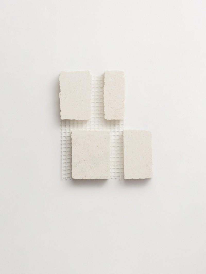 four squares of white soap on a white surface.
