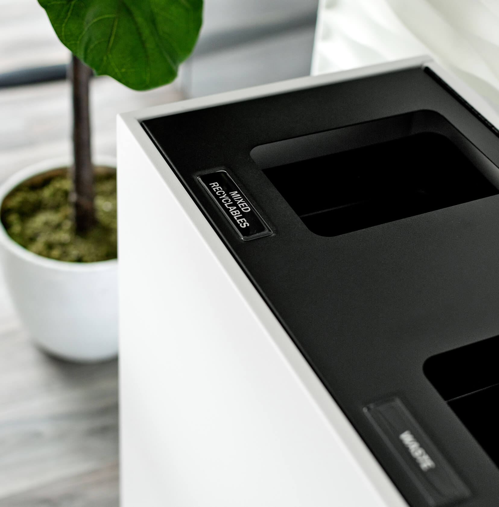 modern metal indoor recycling and trash bin with a white body and black hinged lid in an upscale medical office