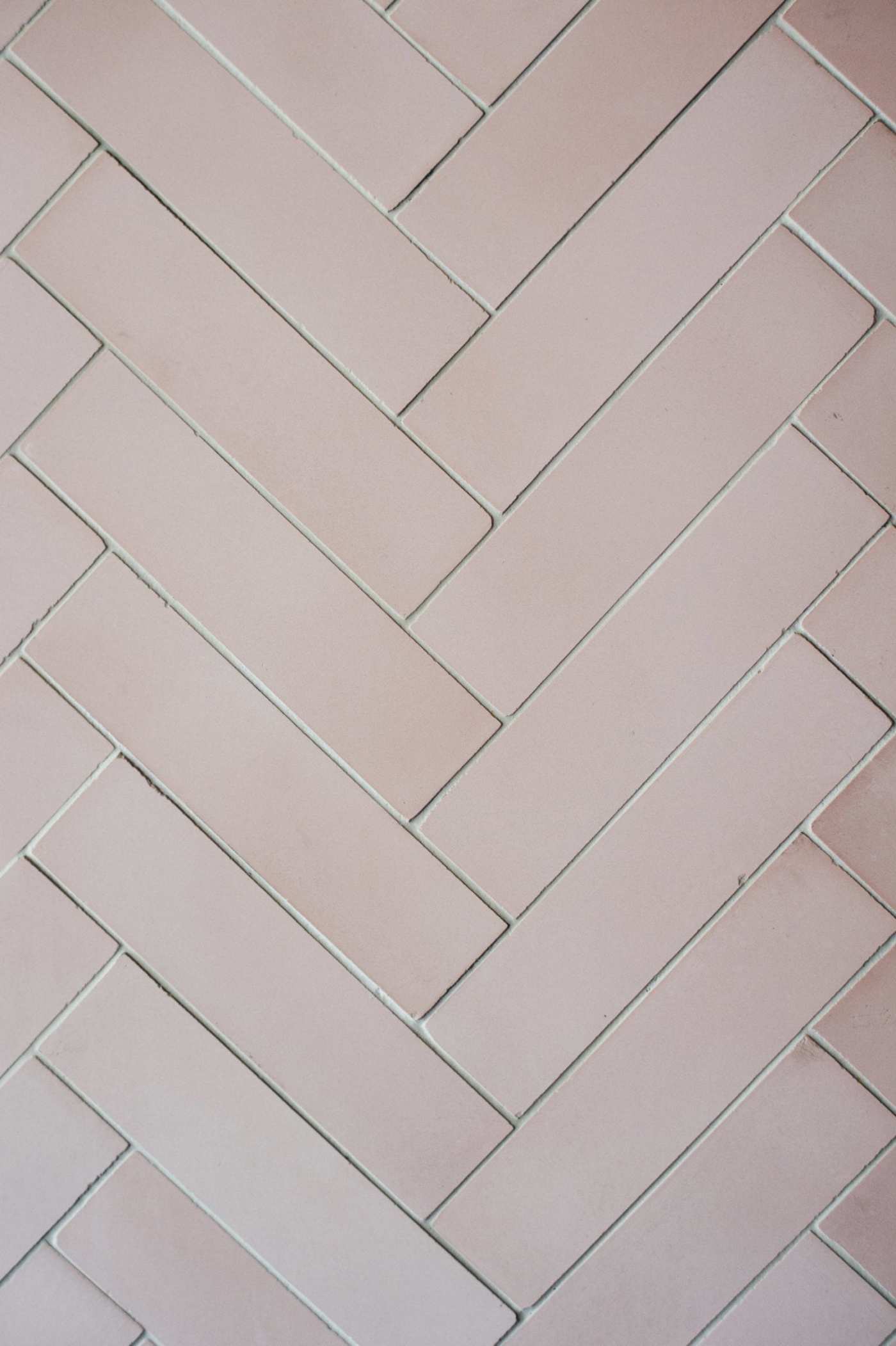 a close up image of a pink herringbone tile.