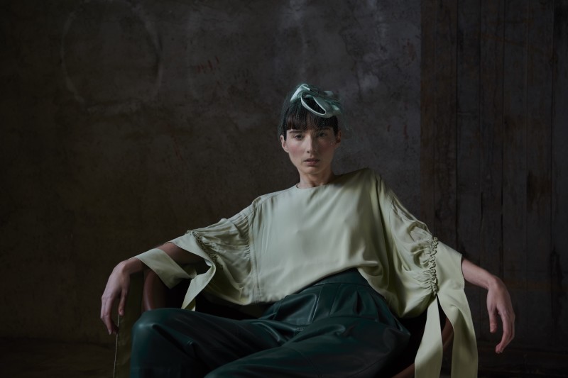 a woman sitting in a chair with green pants.