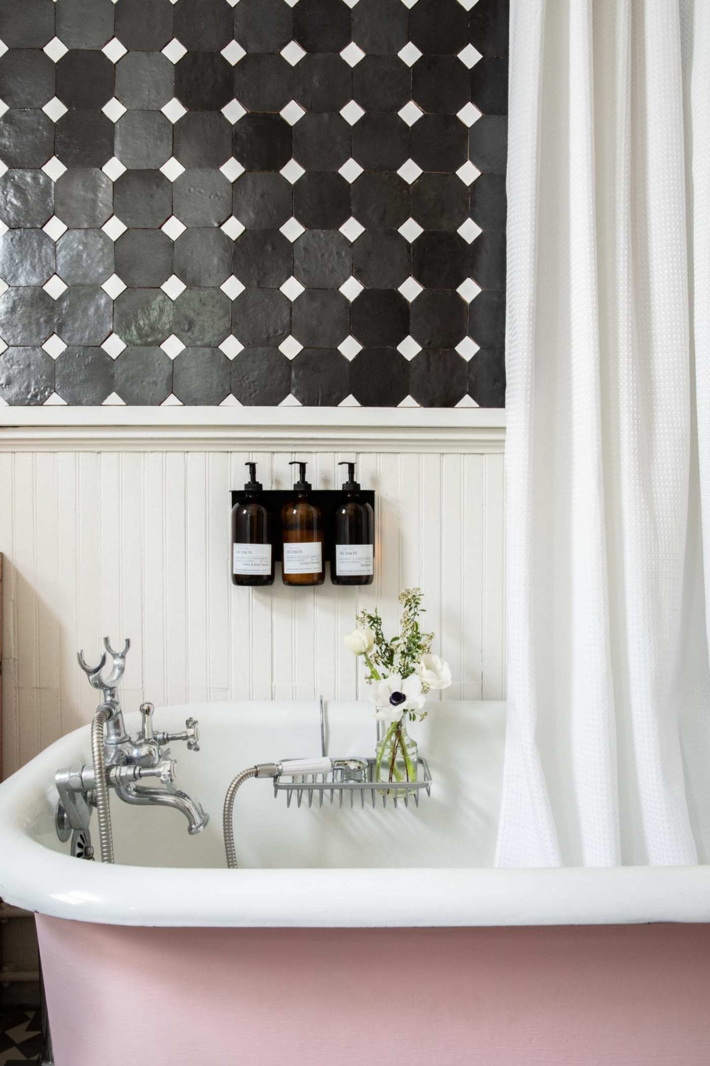 a black and white tiled bathroom with a pink tub.