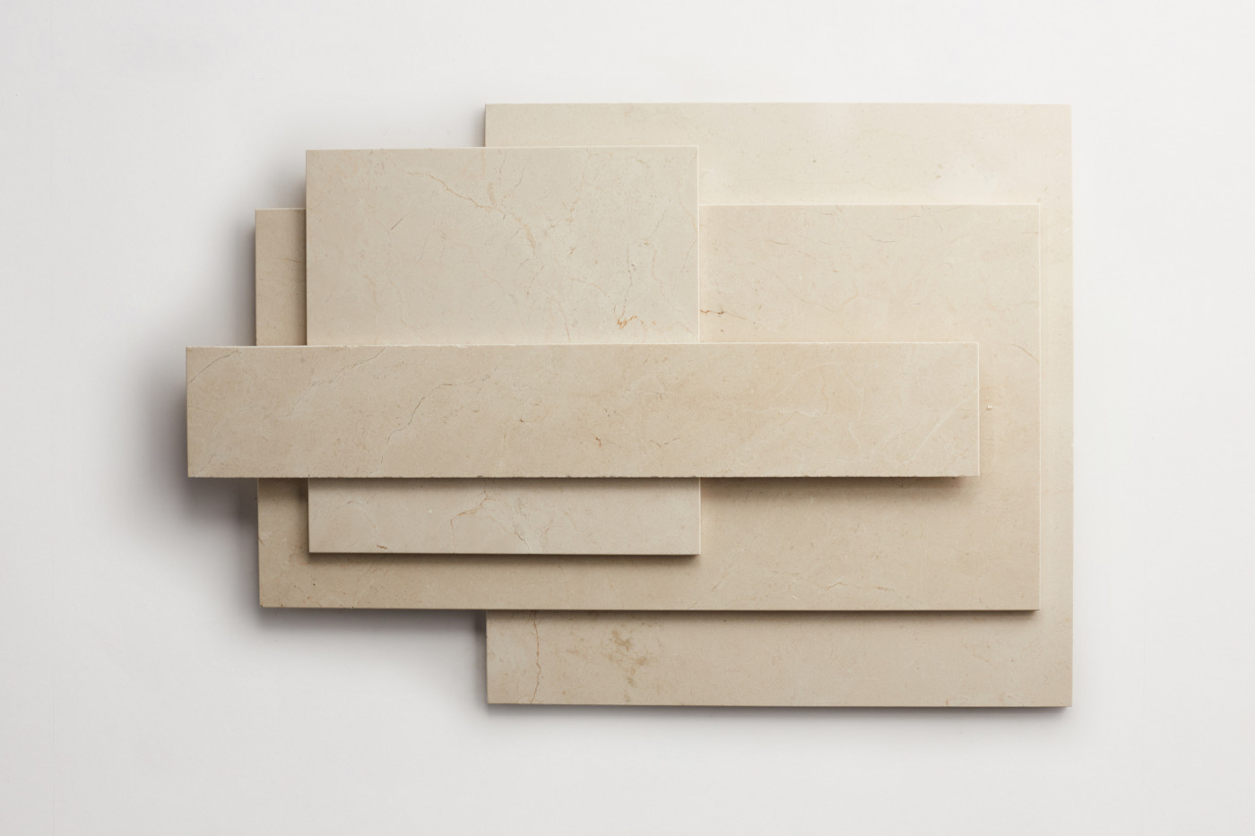 a stack of various sized limestone tiles on a white surface.