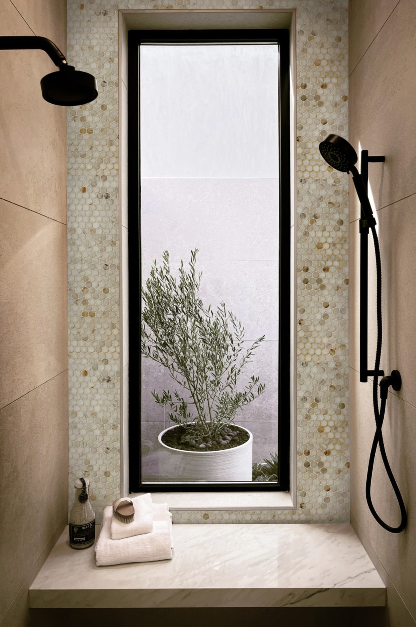 a shower seat in a shower with a window and a shower head.