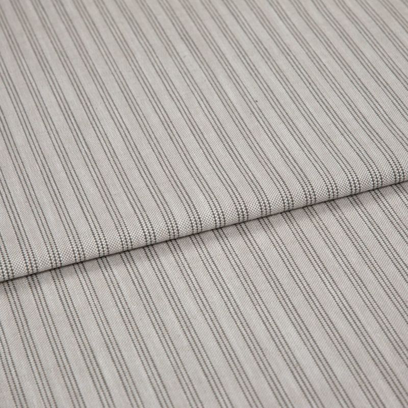 Striped cotton-blend fabric sample, narrow vertical pinstripes in gray on beige, folded once to form a layered edge; close-up studio shot showing woven texture and soft, neutral lighting.