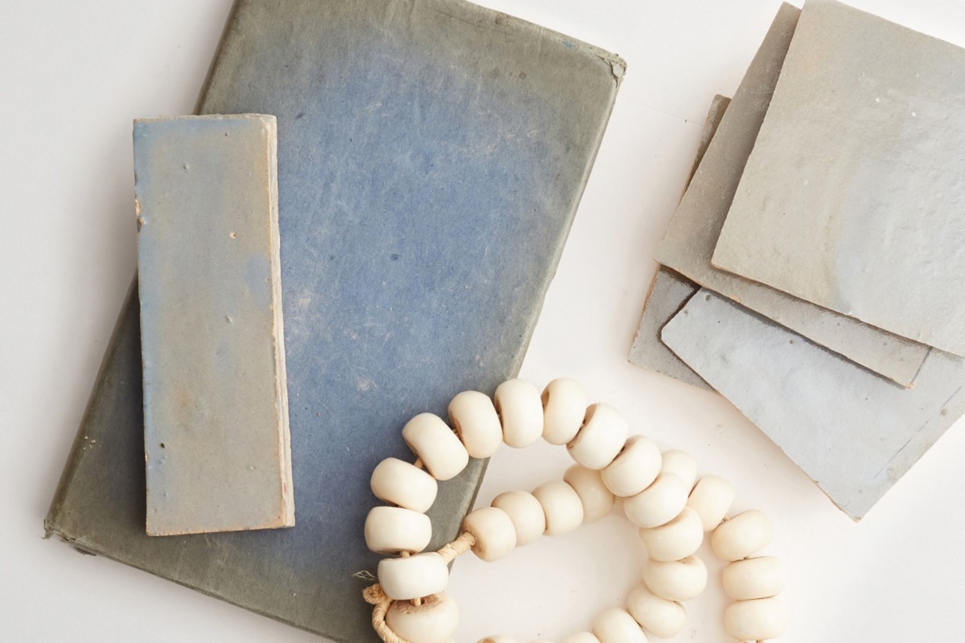 blue tiles and white strnged beads on a white surface.