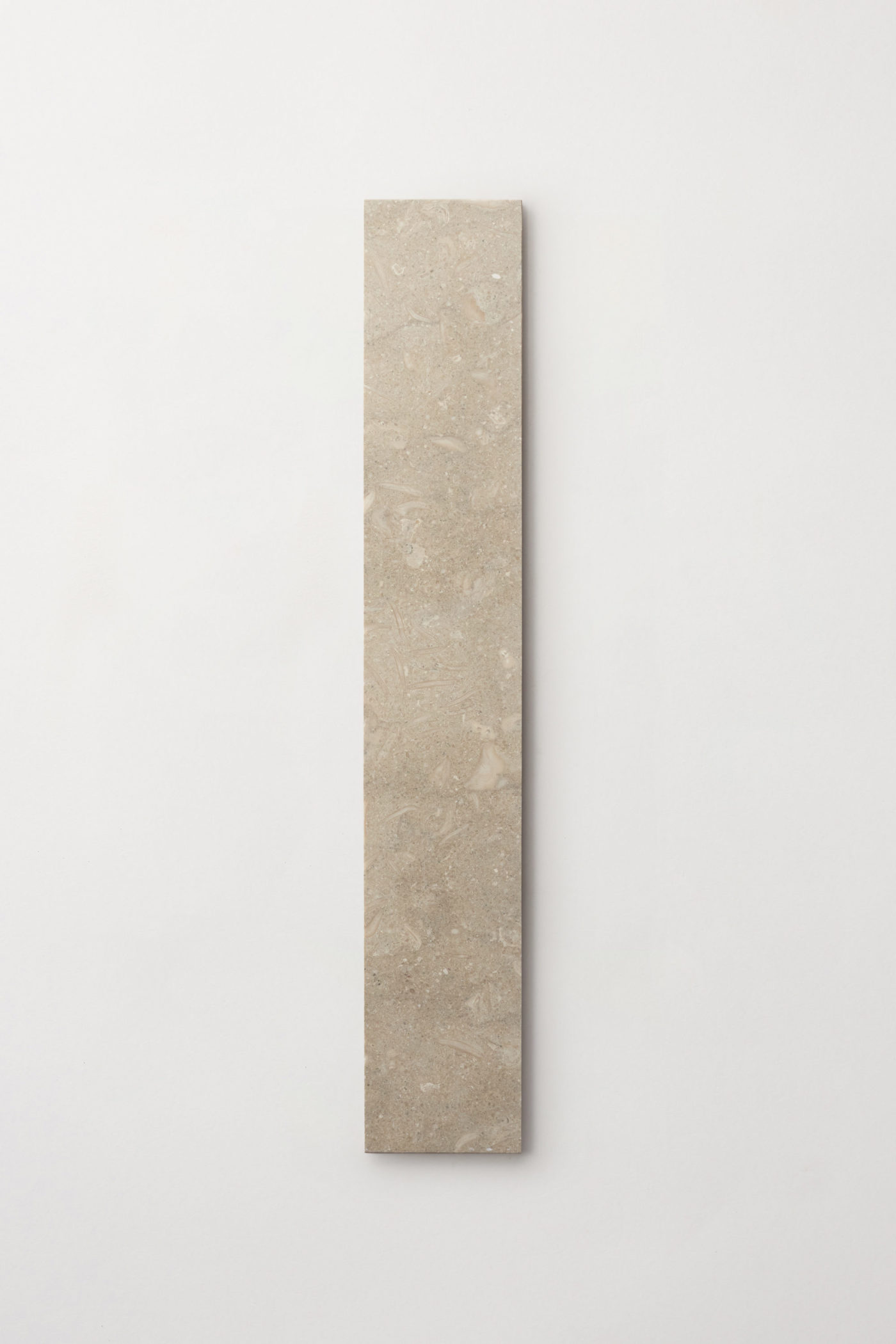 a rectangular piece of beige tile on a white surface.